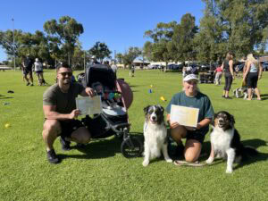 Happy dog trainers with their certified dogs at Agile Dogs training event.