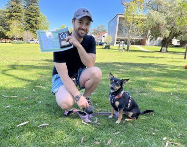 Man with dog training certificate outdoors in park.